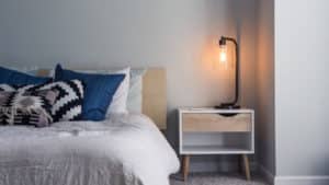 An empty bedroom with the lamp light on used for a Whitney Sleep blog banner advertising home sleep studies