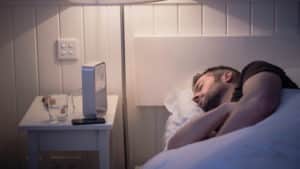Image of man being treated in sleep apnea by Whitney Sleep specialists sleeping in white linen sheets at night