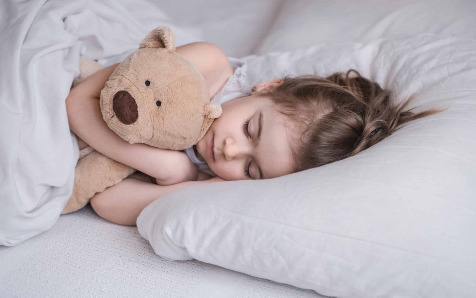 Little cute girl in bed with toy