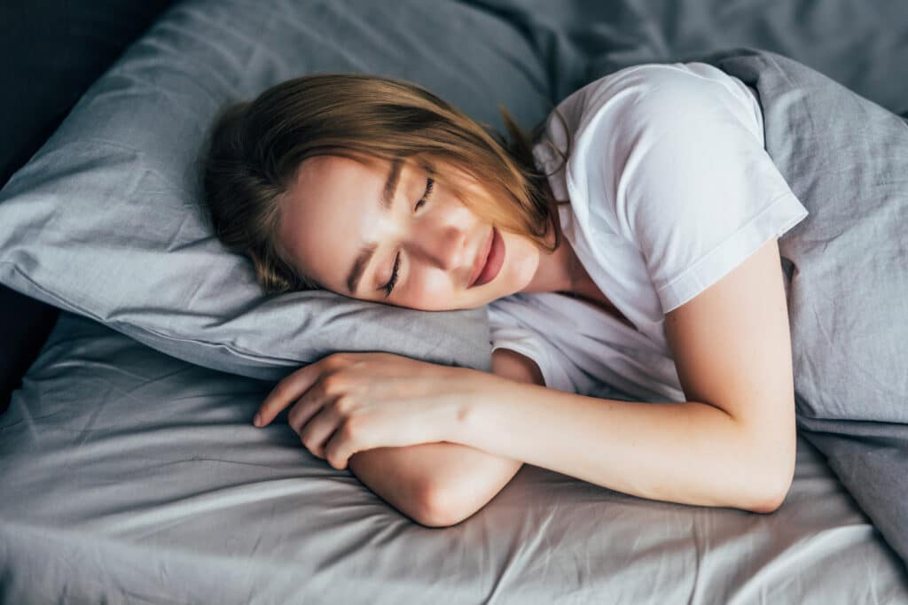 Young smiling woman sleeping in bed